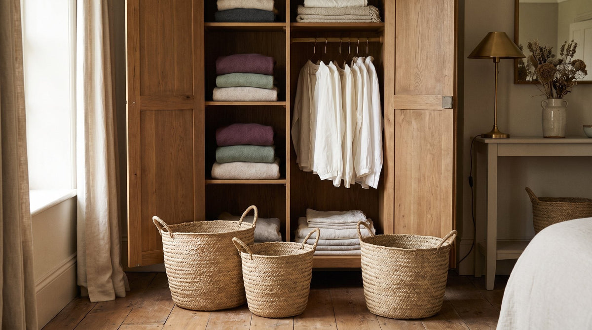 An open wardrobe with three woven baskets on the floor in front of it, soft afternoon light Image