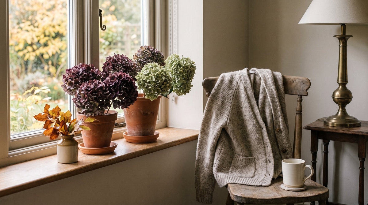 A window with late summer flowers on the sill and the first golden leaves outside, a cardigan on the chair Image