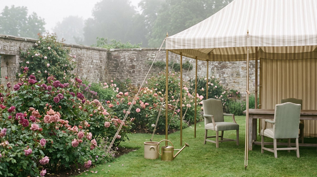 An English walled garden with a striped marquee, rose borders and a lawn set with garden chairs Image
