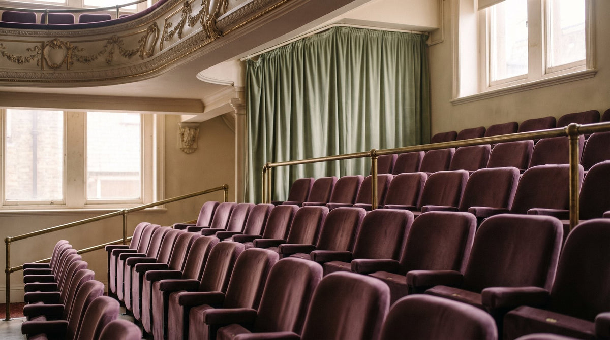 Rows of plush red velvet theatre seats under a gilded balcony Image