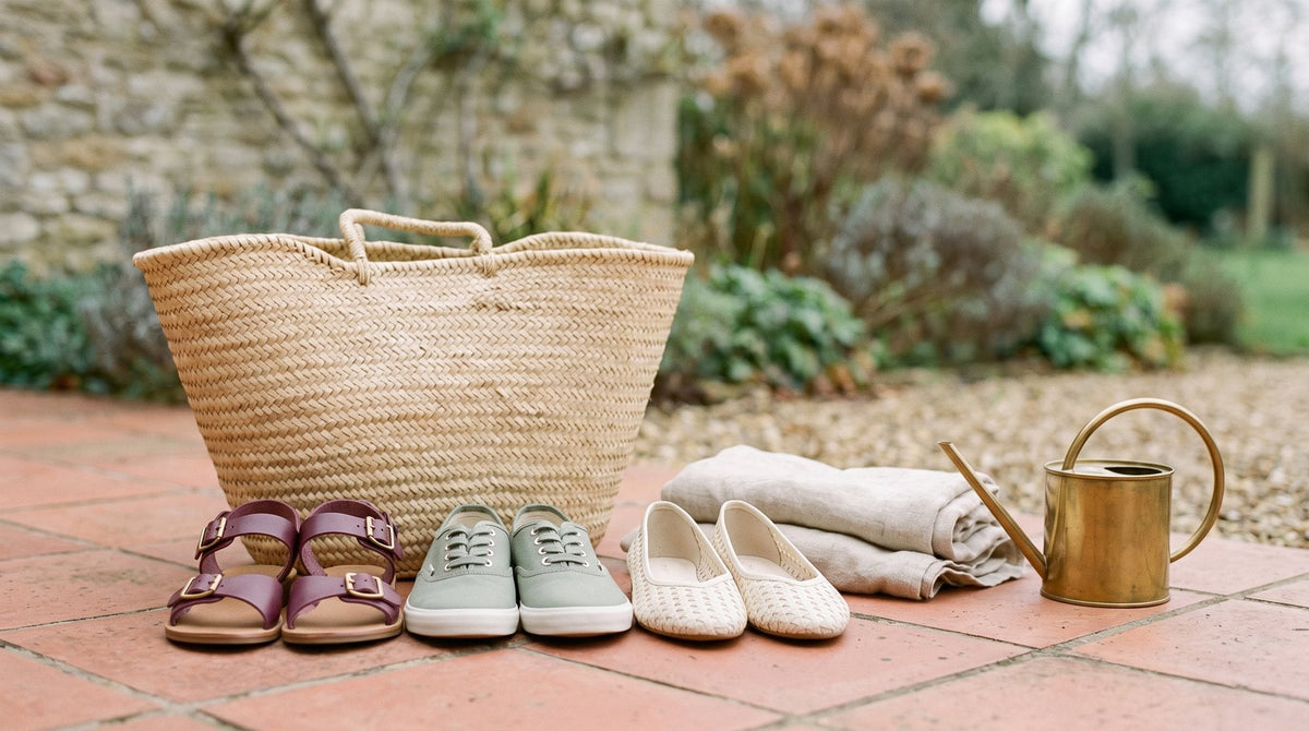 Three pairs of shoes, sandals, flats and trainers, beside a straw-look beach bag on a terracotta terrace