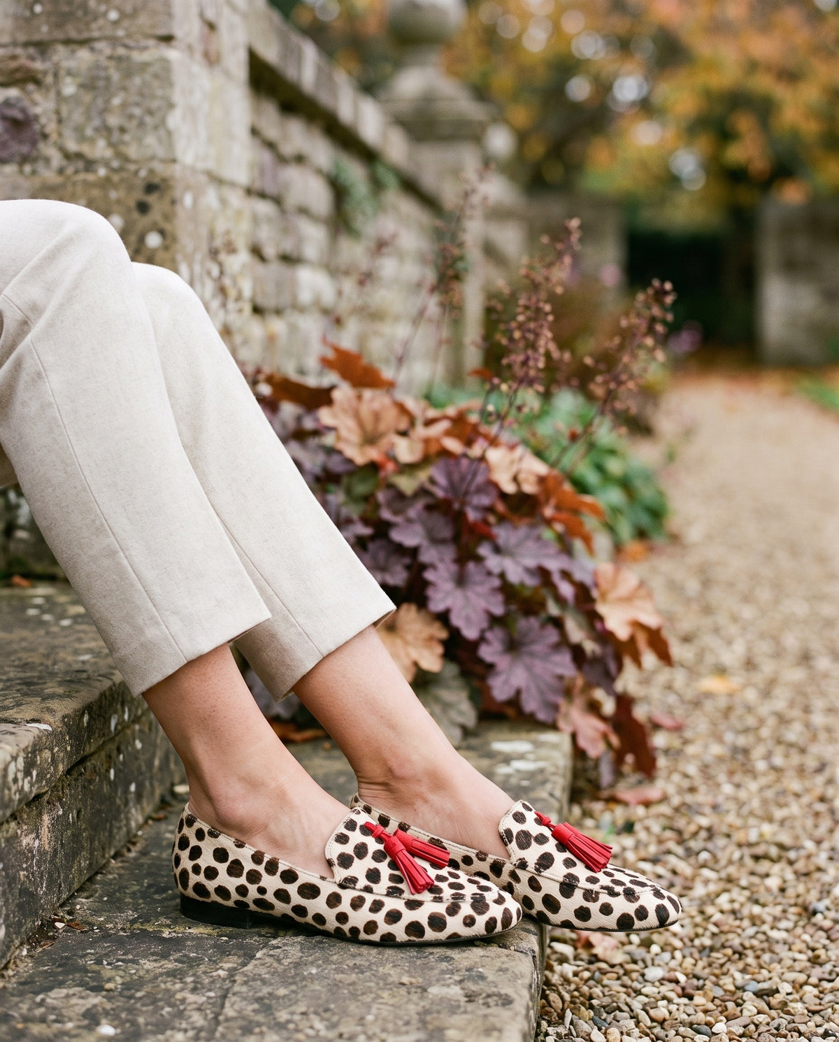 Close-up of feet wearing the orthopaedic slip-on tassel loafers, seated on a stone step