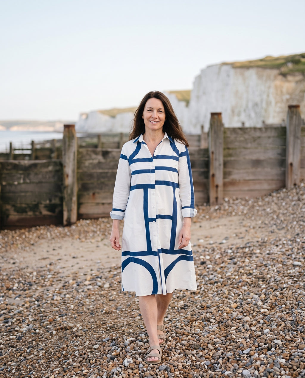 Woman wearing the sophisticated midi dress on an English pebble beach