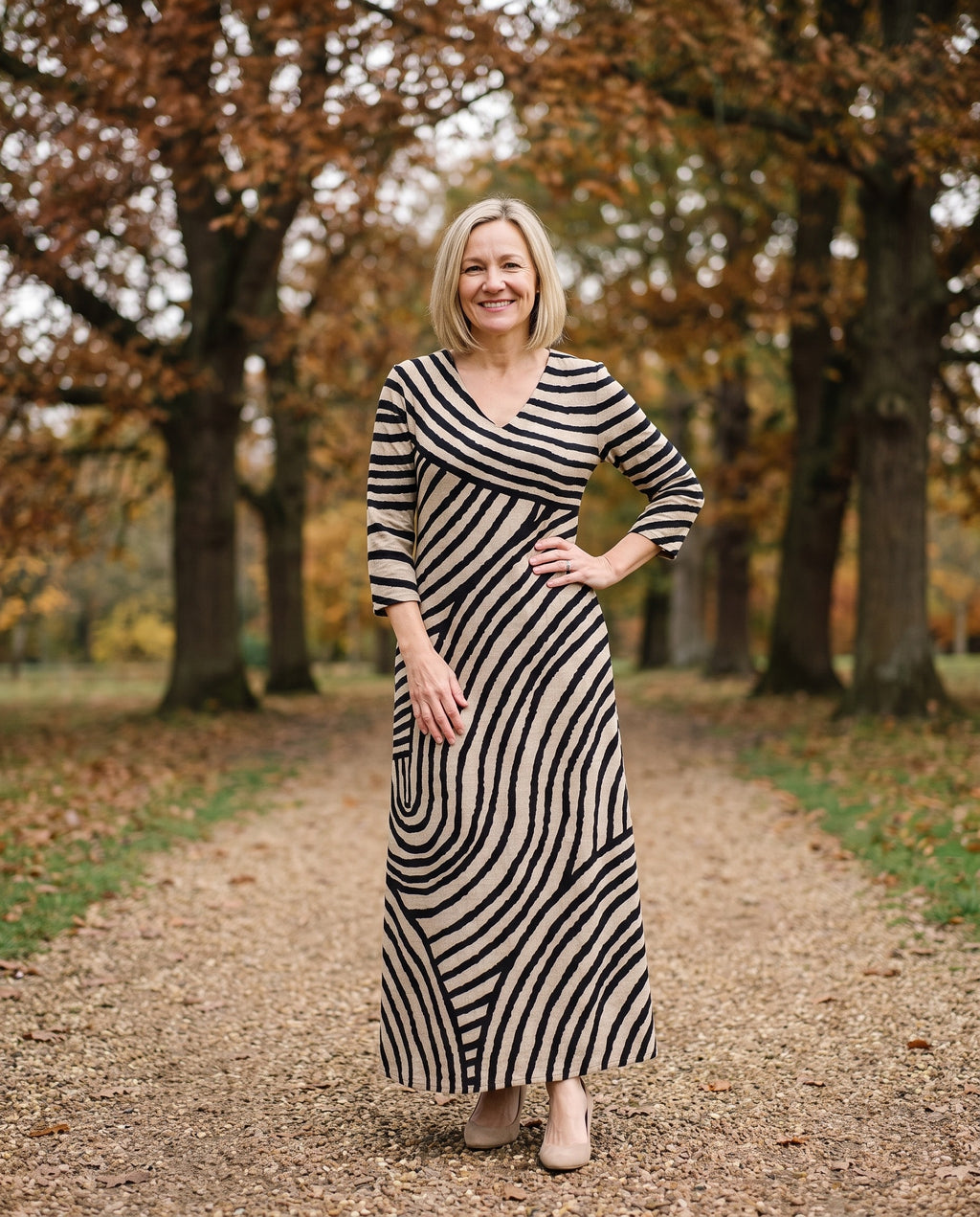 Woman wearing the graphic print maxi dress with v-neck and pockets in an English park in autumn