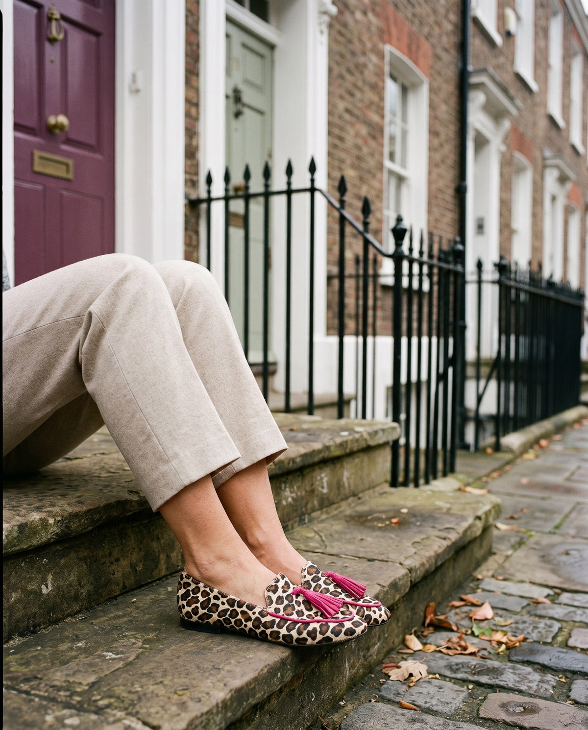 Close-up of feet wearing the slippers with fringe details, seated on a stone step Image