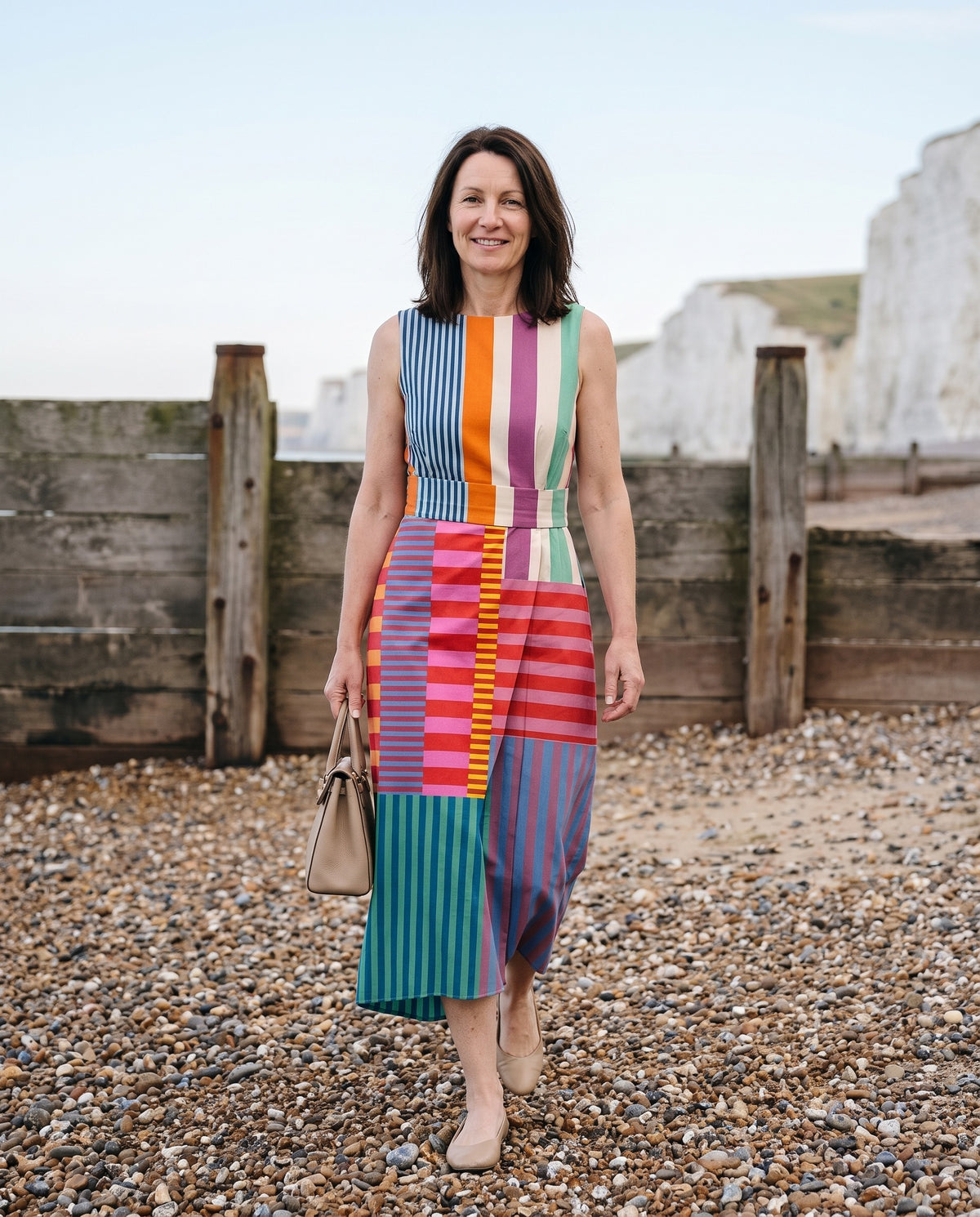 Woman wearing the patchwork stripe midi dress, sleeveless on an English pebble beach Image