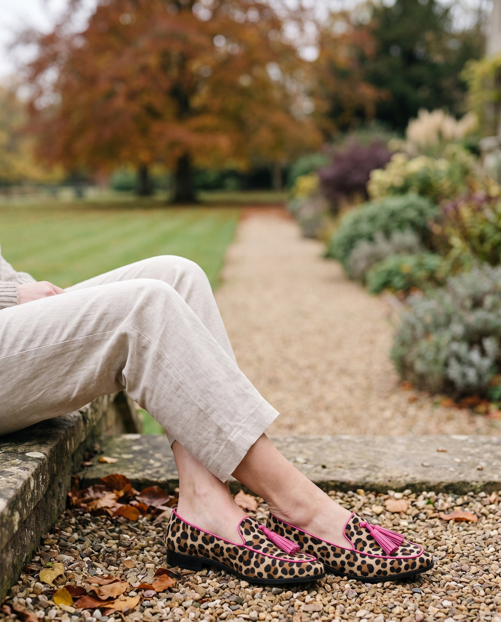 Close-up of feet wearing the fringe detail slippers, seated on a stone step