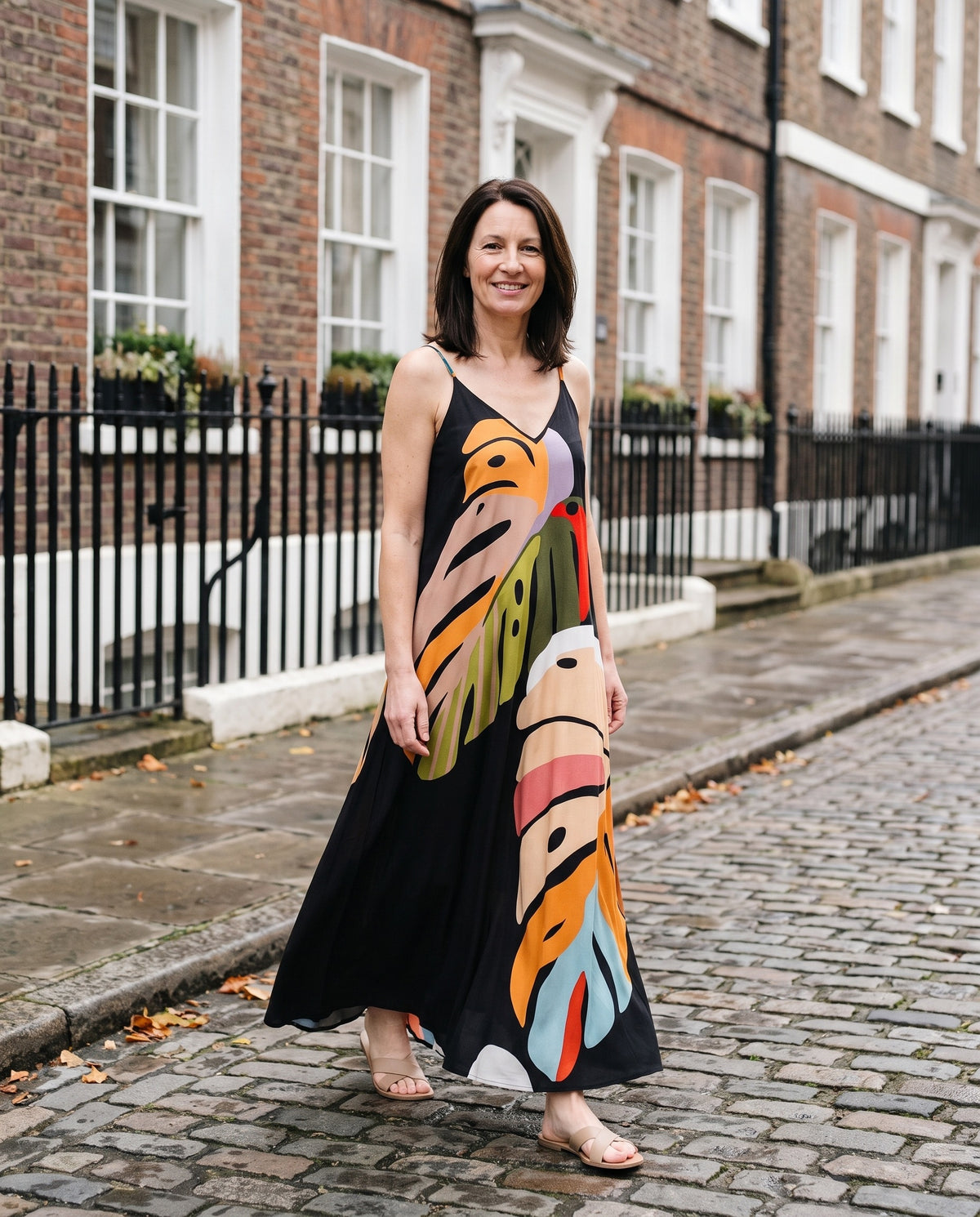Woman wearing the tropical leaf print maxi dress, v-neck on an English residential street