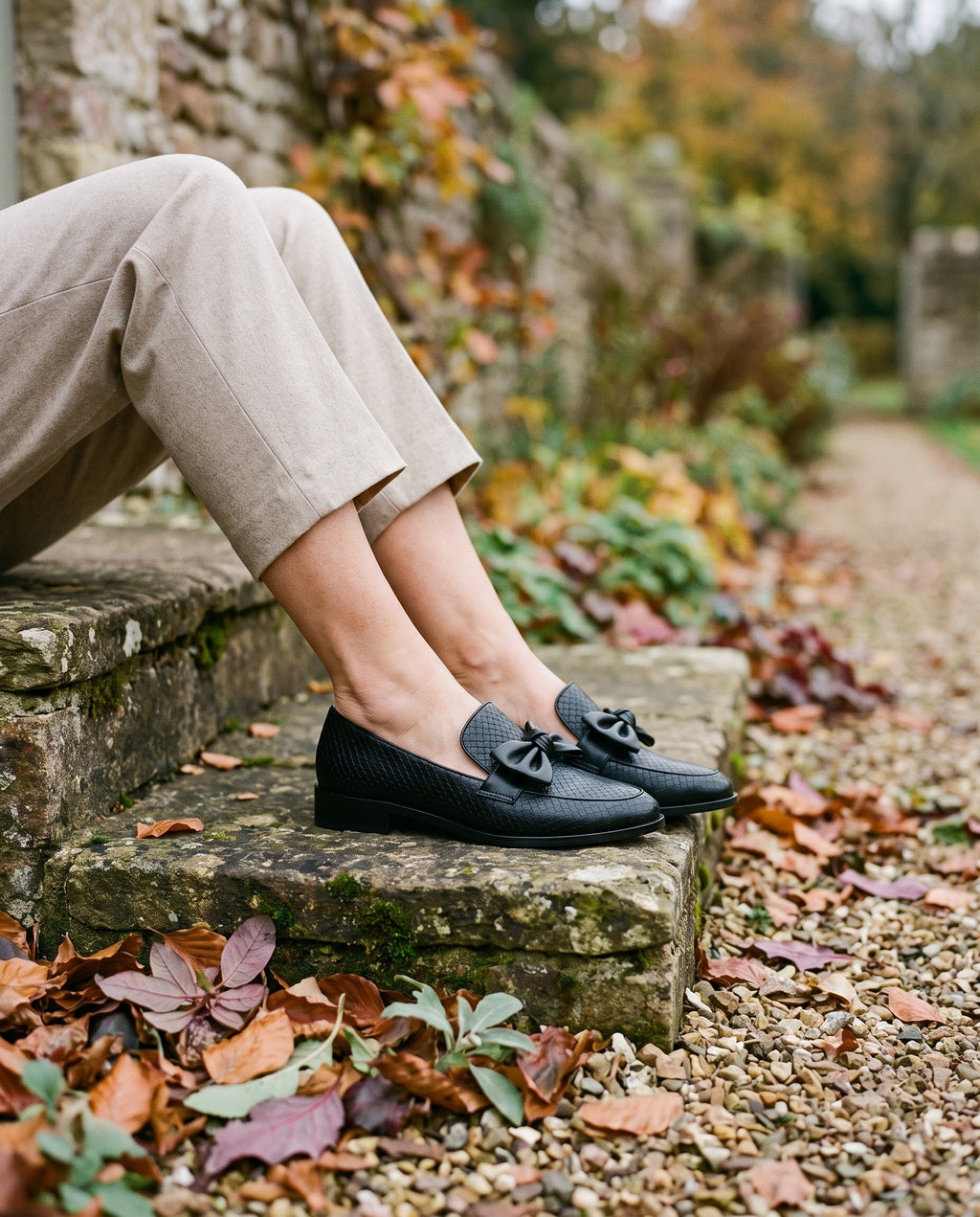 Close-up of feet wearing the luxe comfort loafers, seated on a stone step