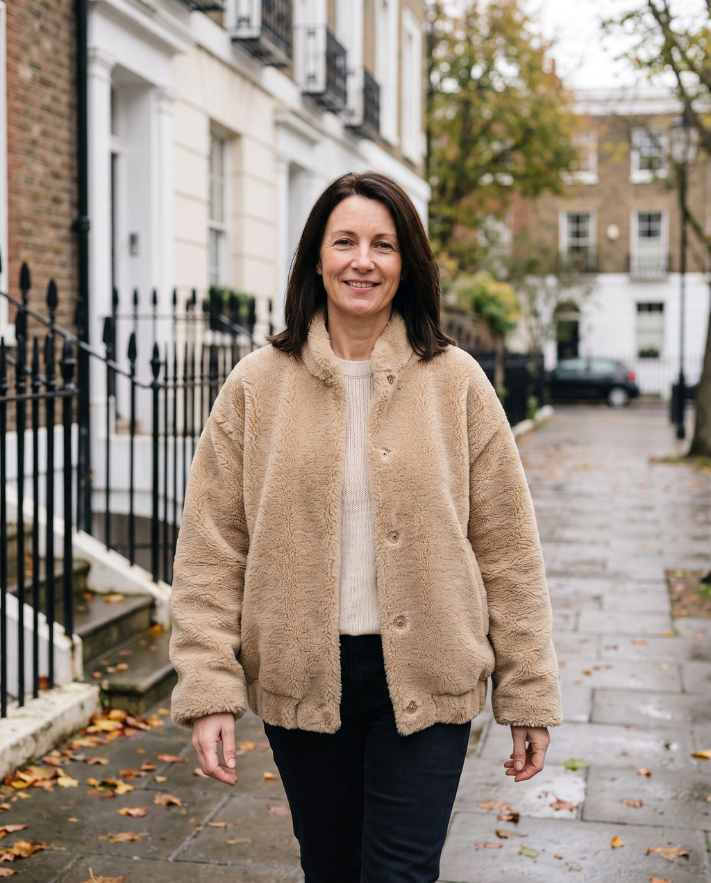 Woman wearing the oversized teddy jacket with button closure on an English residential street