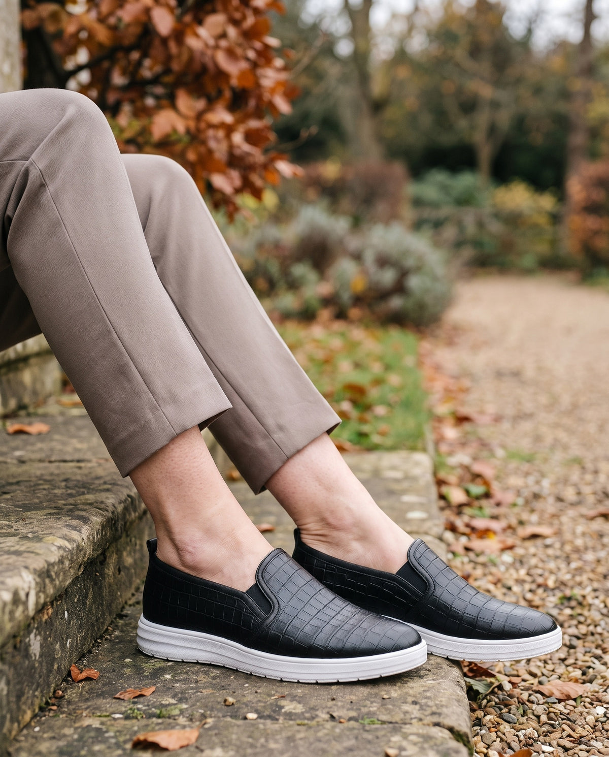 Close-up of feet wearing the supportive style loafers, seated on a stone step Image
